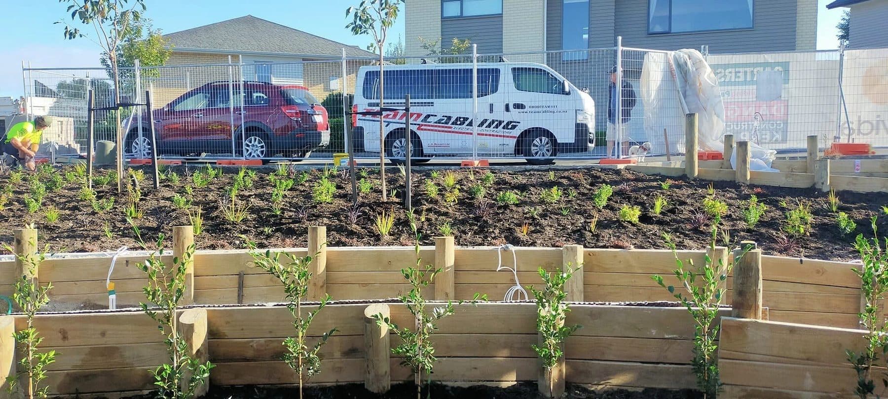 Timber raised planter boxes newly planted along a commercial building frontage